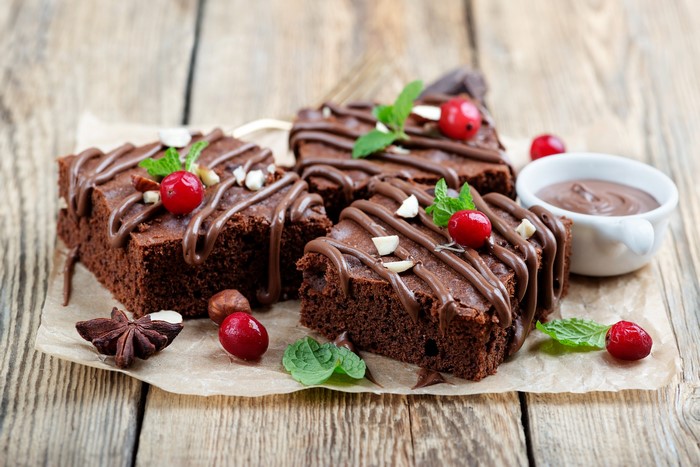 Chocolate brownies with berries and nuts on a wooden surface