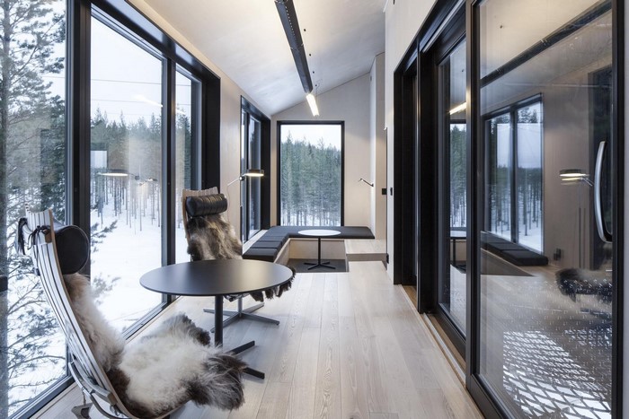 Modern interior with large windows overlooking a snowy forest