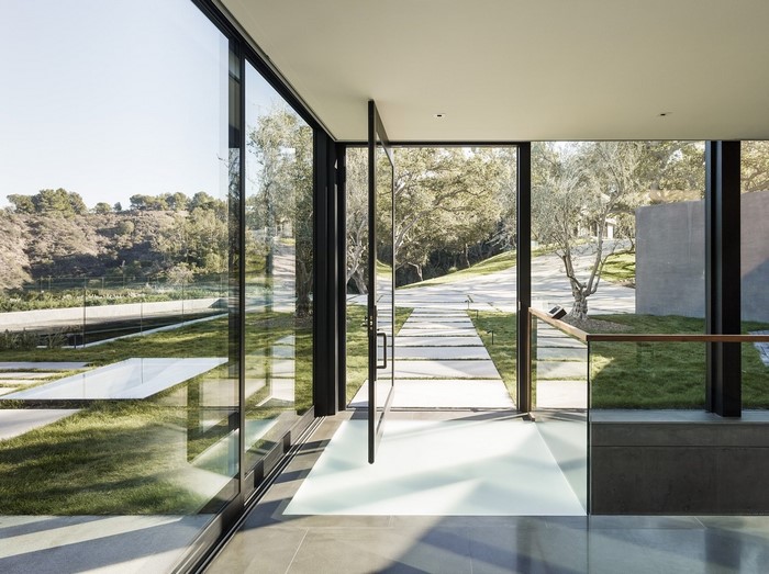 Modern glass house entrance with outdoor pathway