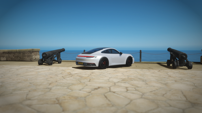 Porsche 911 992 on a sunny coast with cannons