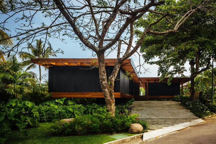 Modern house with wooden roof surrounded by tropical plants