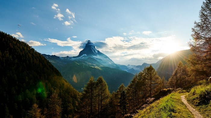 Matterhorn mountain in Switzerland with paraglider and sun rays