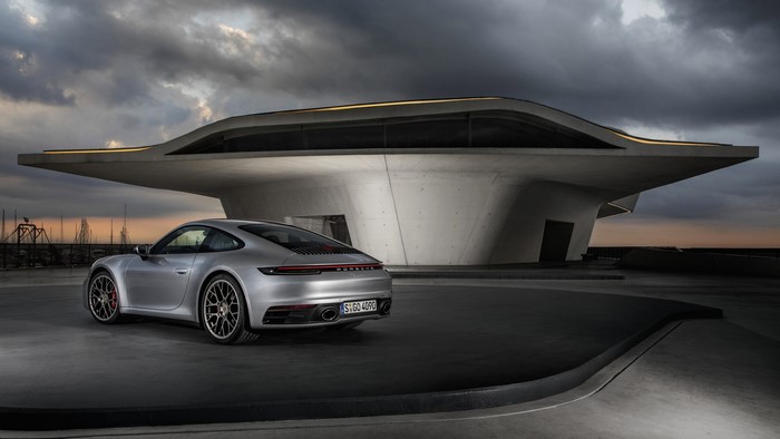 Silver Porsche 911 parked near a modern building