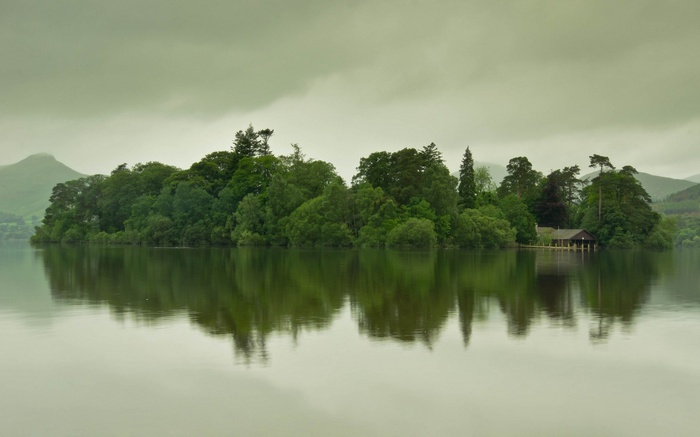 Island with trees and a boathouse on a lake