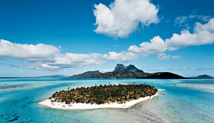 Tropical island with palm trees and mountains in the sea