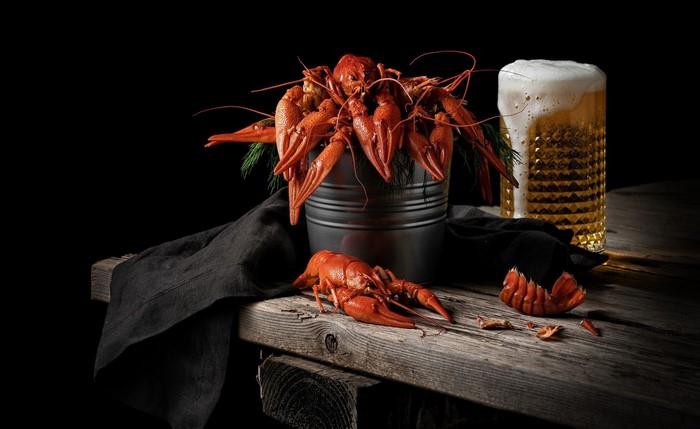 Cooked crawfish in a bucket with a glass of beer