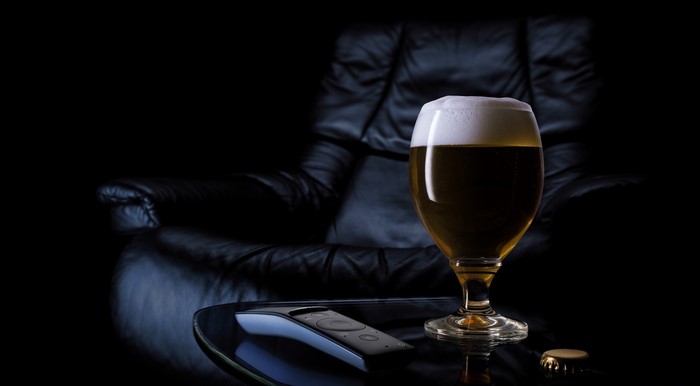 Glass of beer on a table with a remote