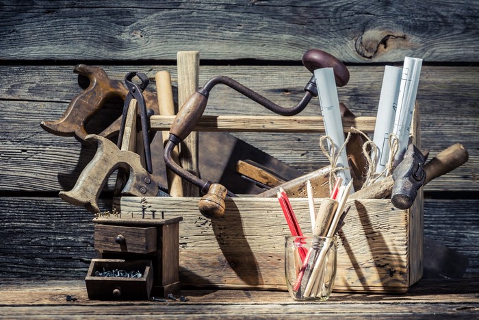 Vintage toolbox with saws, hammer, and blueprints