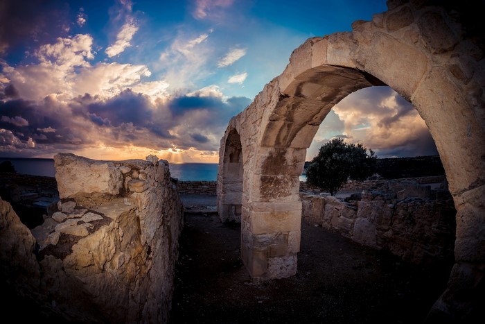 Ancient stone arches overlooking the sea at sunset