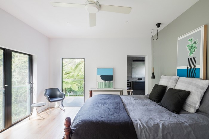 Modern bedroom with a bed, chair, and artwork