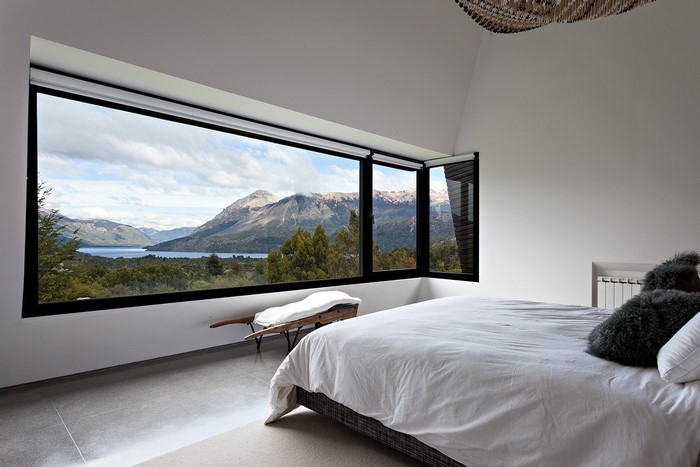 Bedroom with a large window overlooking mountains and a lake