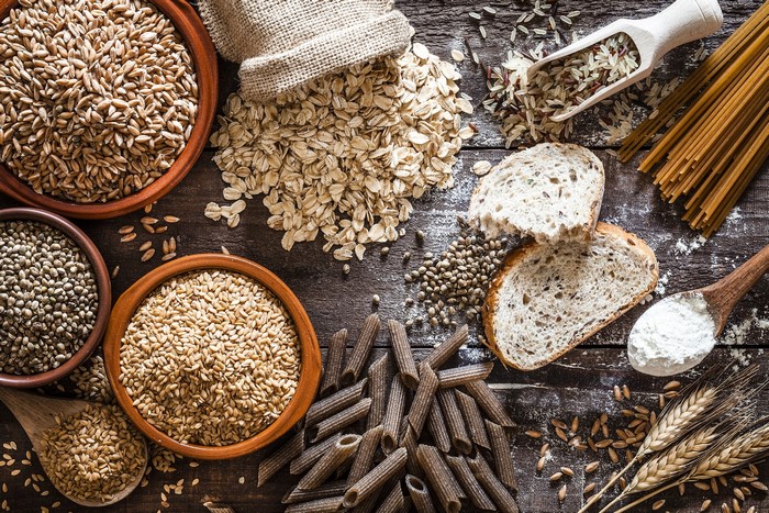 Assortment of grains, pasta, bread, and flour on wooden surface