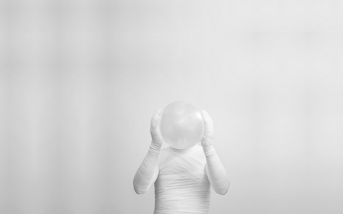 Person wrapped in bandages holding a balloon