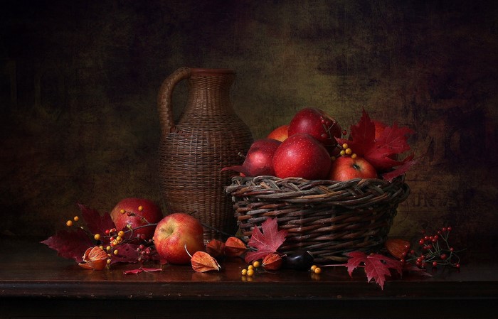 Still life of apples in a basket with a woven jug
