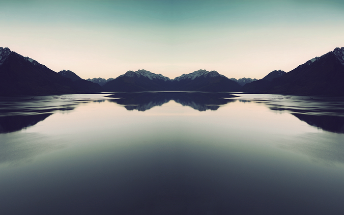 Symmetrical mountain range reflected in a calm lake