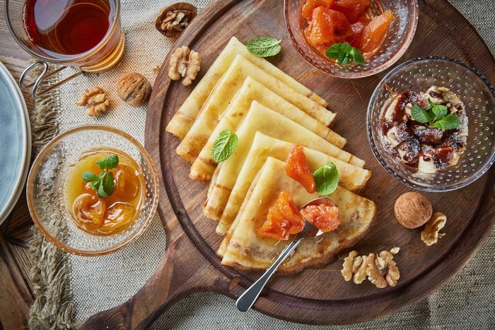 Crepes with fruit and walnuts on a wooden board