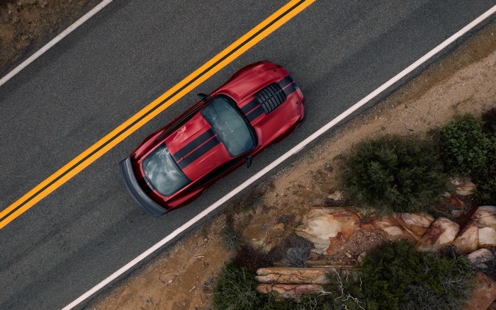 Red sports car with black stripes on a road
