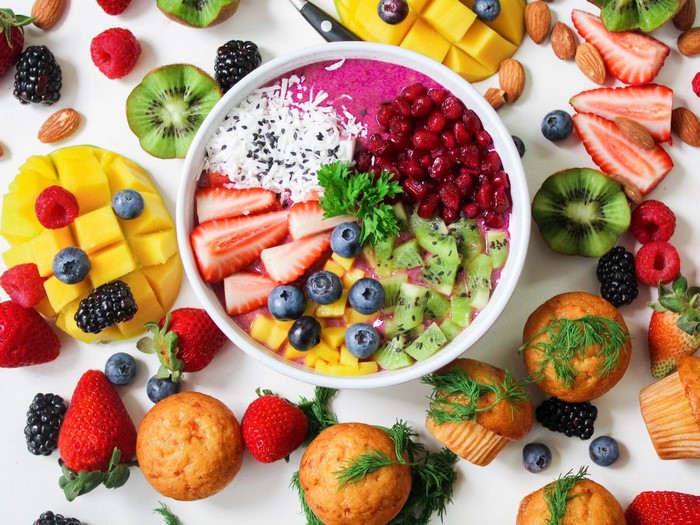 Fruit bowl with strawberries, kiwi, mango, pomegranate, and muffins