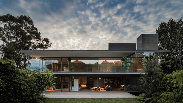 Modern glass house with concrete elements and trees