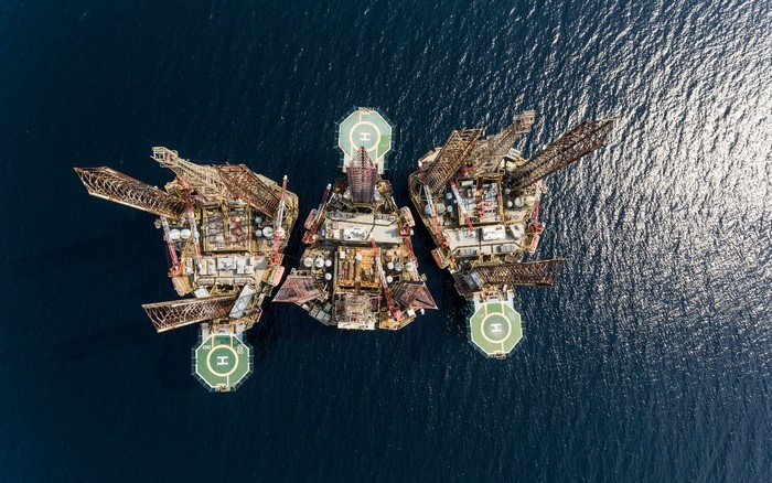 Aerial view of three offshore oil platforms in the sea