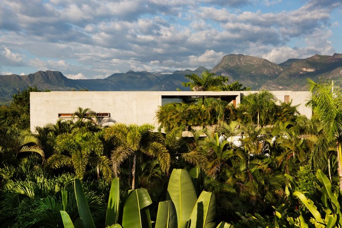 Modern house surrounded by lush vegetation with mountains in the background