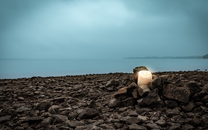 Candle on a rocky shore by the lake