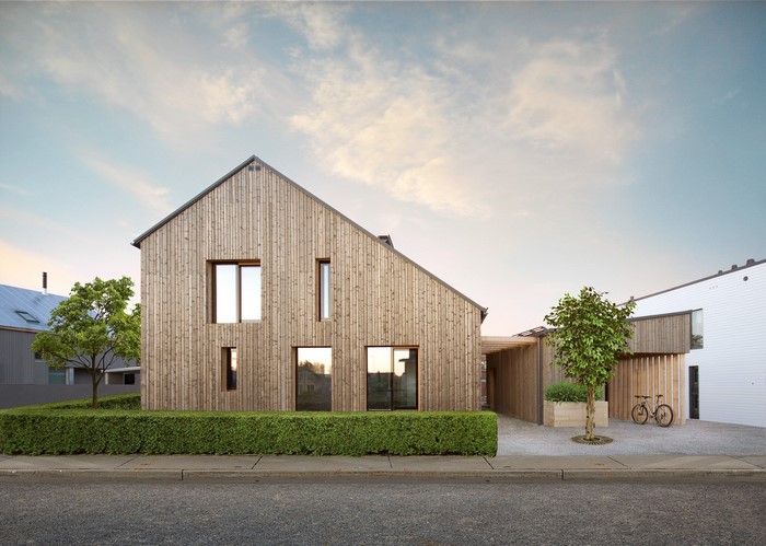 Modern wooden house with bicycle and hedge