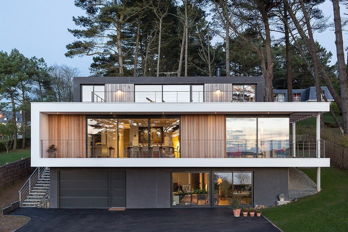 Modern multi-story house with large windows and trees