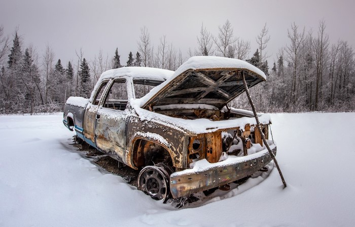 Abandoned snow-covered truck in winter forest