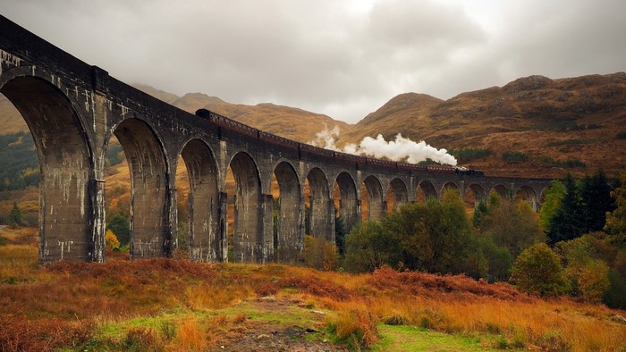 Steam train crossing a stone viaduct in Scotland