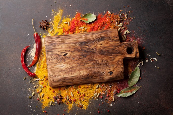 Wooden cutting board with colorful spices and chili peppers