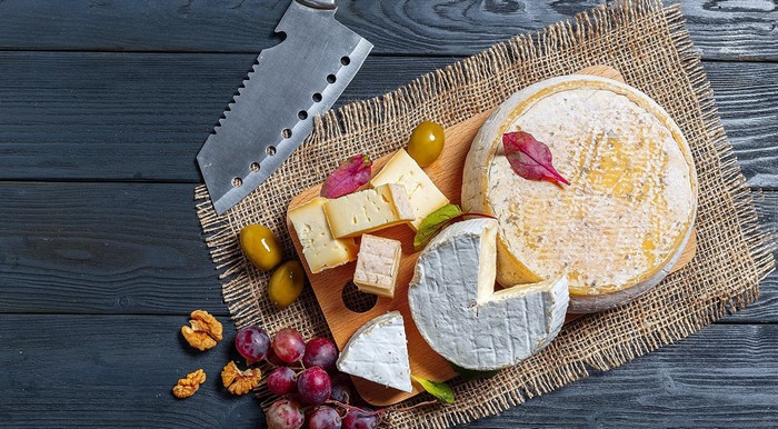 Cheese board with olives, grapes, walnuts, and knife