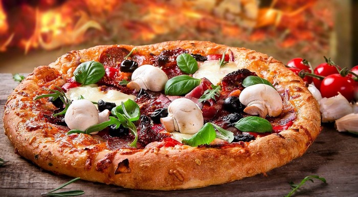 Pizza with mushrooms, olives, basil, and tomatoes