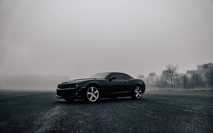 Black Chevrolet Camaro on asphalt in mist