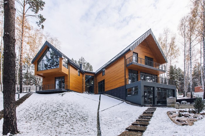 Modern wooden house with large windows in a snowy forest