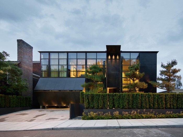 Modern black house with large windows and hedge