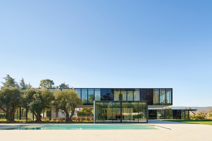 Modern glass house with swimming pool and trees