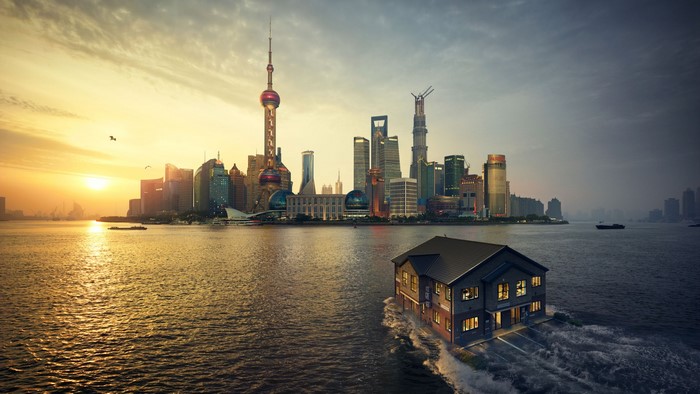 House floating in water with Shanghai skyline at sunset