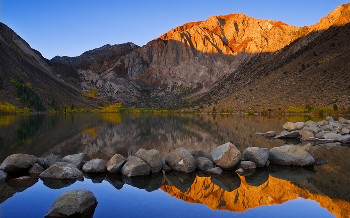 Mountain lake at sunrise with rocks in foreground