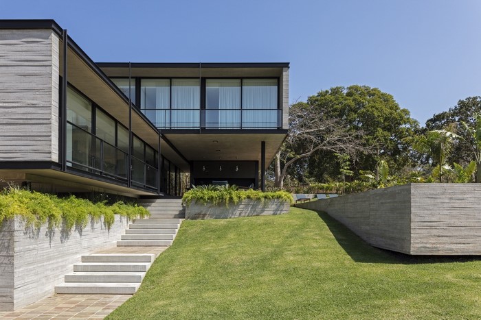 Modern concrete house with large windows and green lawn