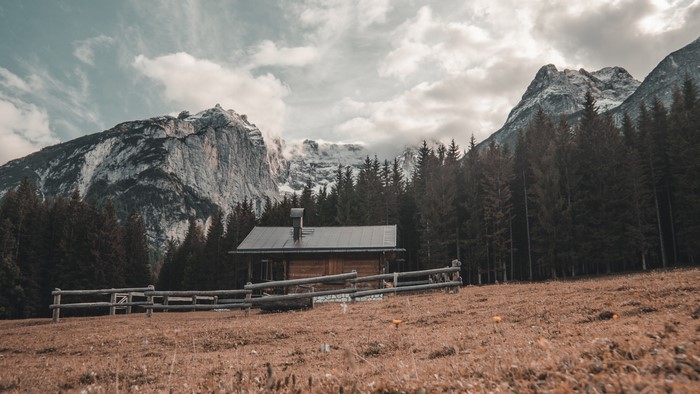 Wooden cabin in a mountain landscape with trees and clouds