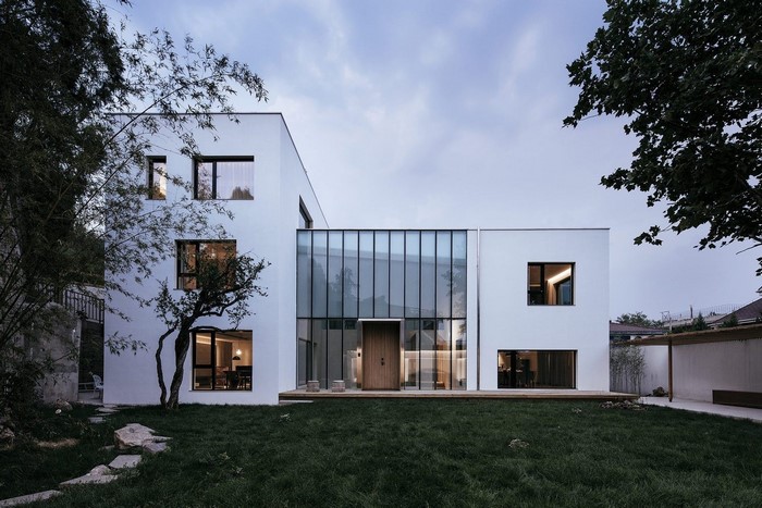 Modern white house with glass facade and green lawn