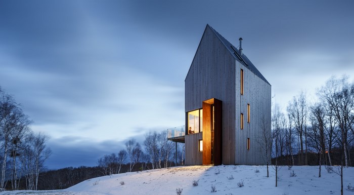 Modern wooden house in snow at dusk