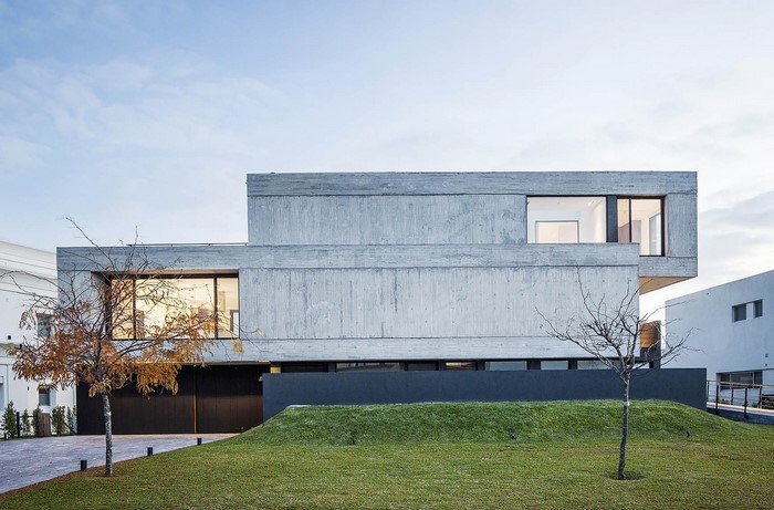 Modern concrete house with large windows and lawn
