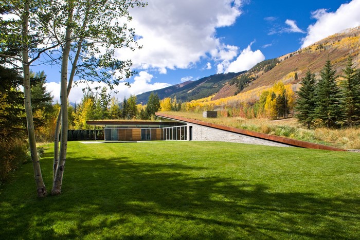 Modern house with green roof in autumn mountain landscape
