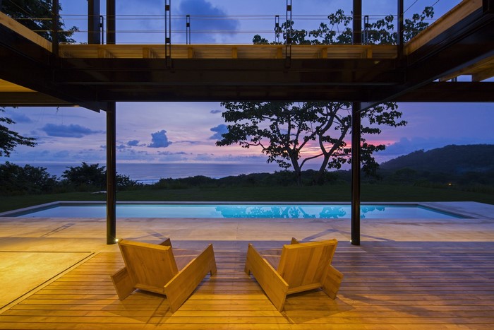 Modern house with swimming pool and ocean view at dusk
