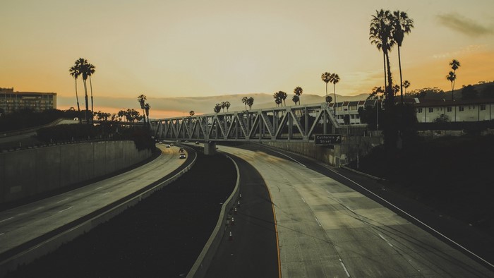 California freeway overpass with palm trees at sunset