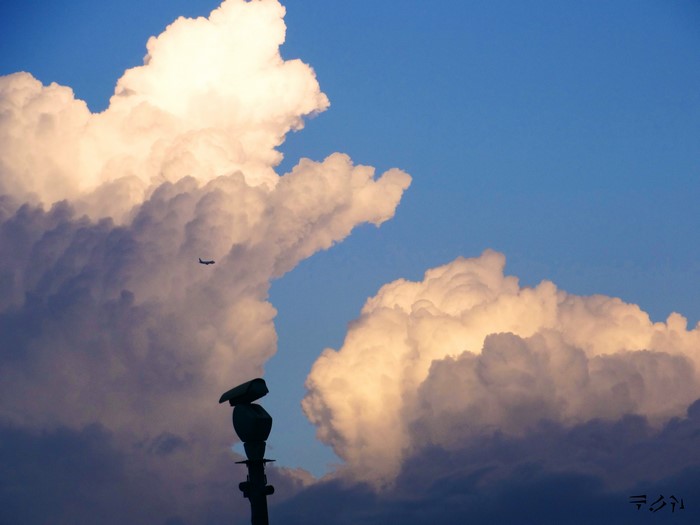 Airplane flying near clouds with statue