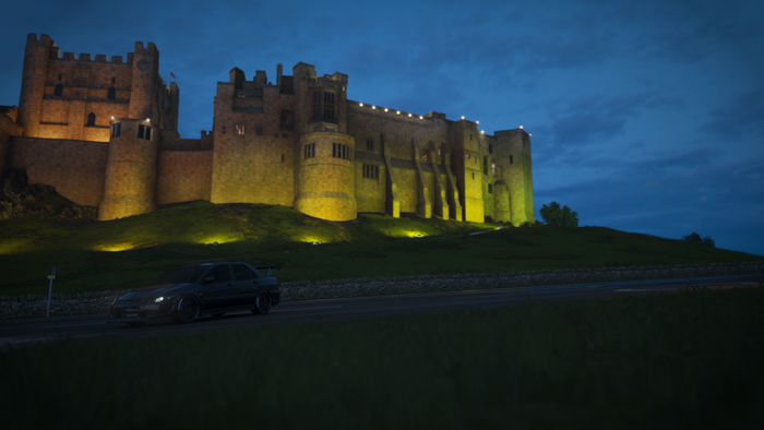 Mitsubishi Lancer EVO in front of illuminated castle at dusk