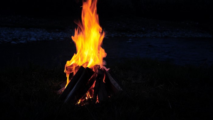 Campfire burning at night by a river